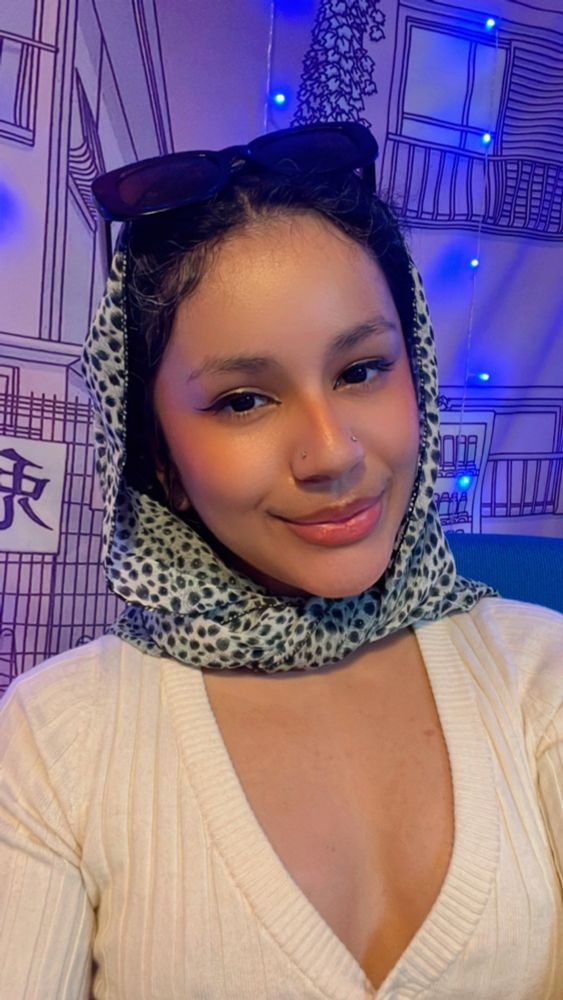 Sopa is wearing a printed scarf around her head reminiscent of an old Hollywood style. She’s smiling softly into the camera. 