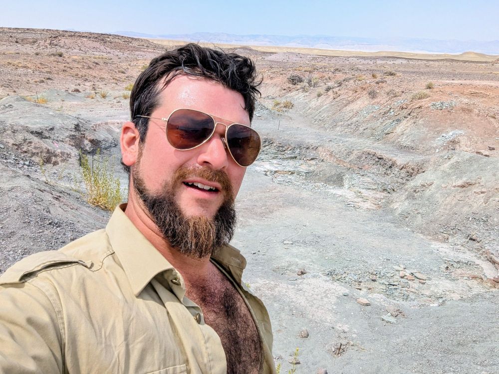 Selfie photo of me, wearing sunglasses, in front of a big ol' hole in the ground in the middle of the eastern Utah desert