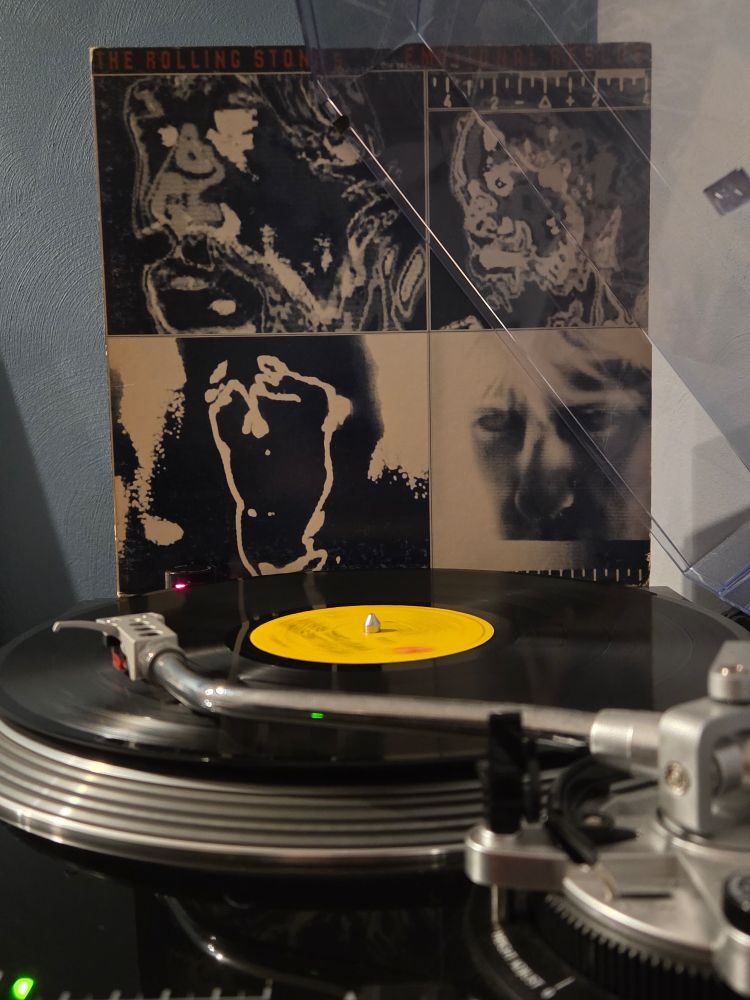 Side view of a black AT-LP120 spinning Emotional Rescue, its jacket propped up against the dust cover in the background 