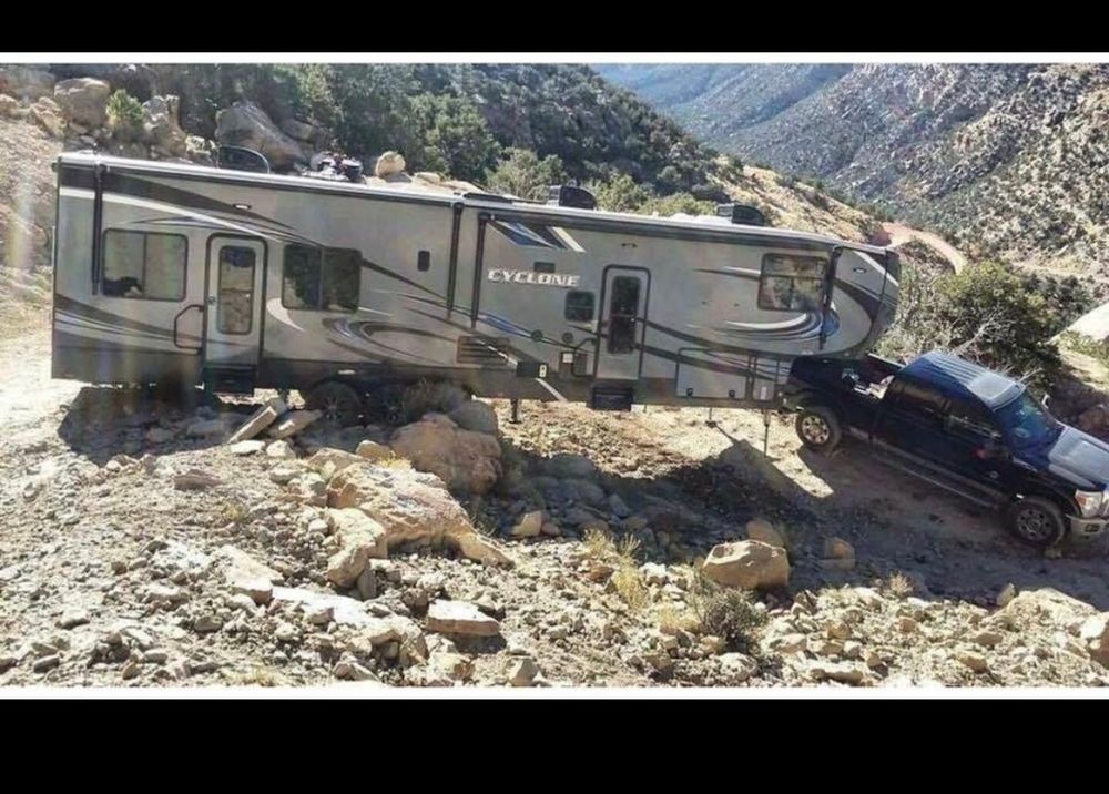 An at least 30 foot long trailer stuck on rocks after trying to get around a MINING ROAD switchback.