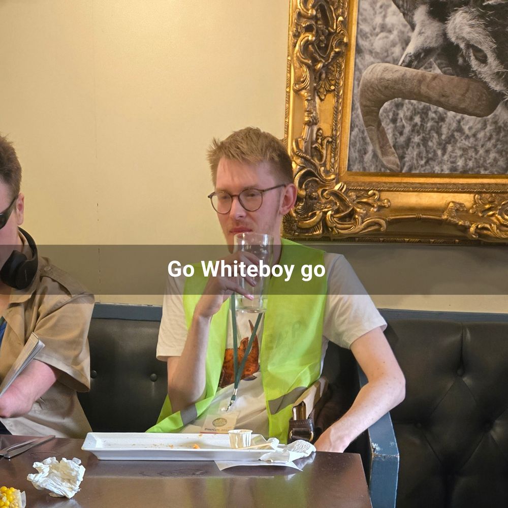 paleoartist joschua Knüppe in a high-vis jacket holding an ale with the caption "go whiteboy go"