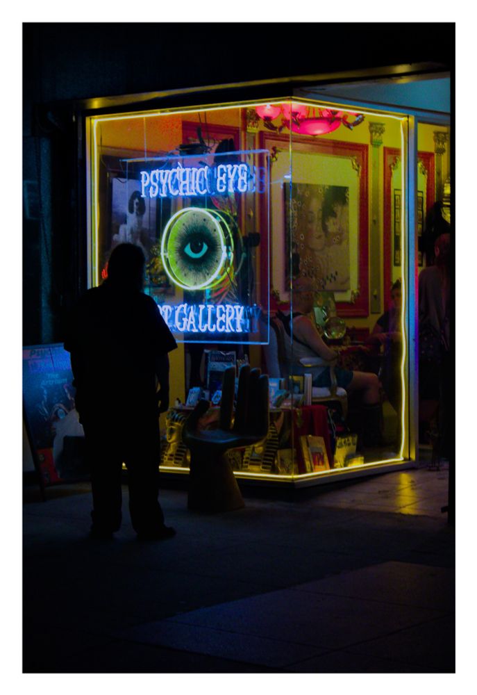 A man stares at a psychic's neon sign on a window. 