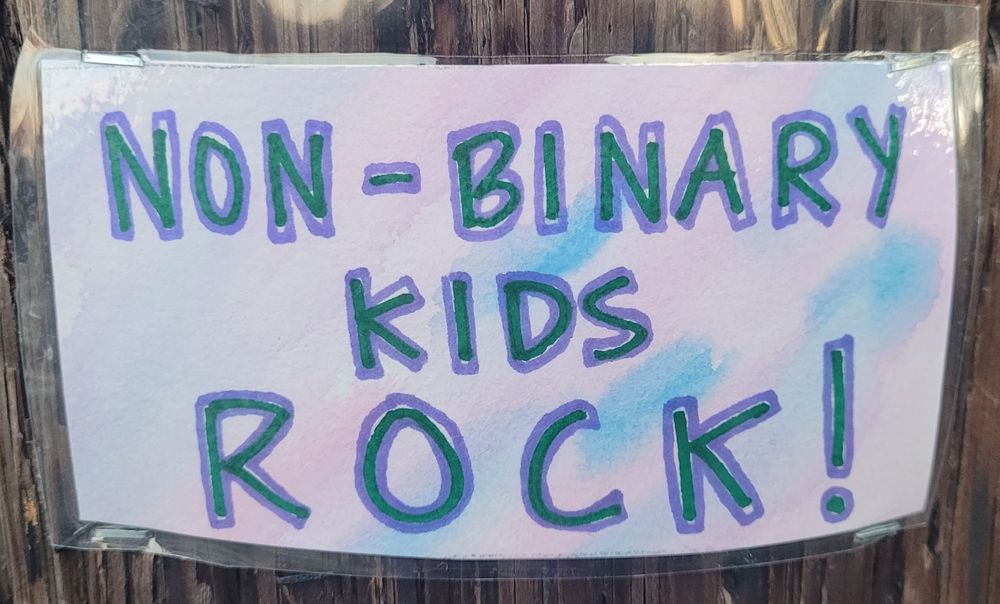 Water color post card with the words, "Non-binary kids rock!"

Water color swatches of pink and blue.