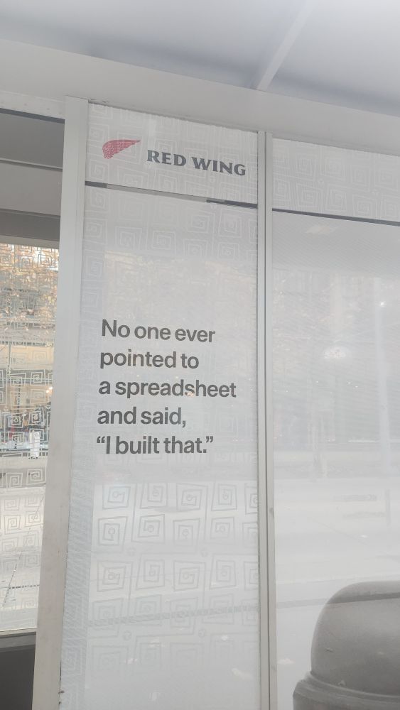Red Wing shoes sign that reads "No one ever pointed to a spreadsheet and said 'I built that.'c