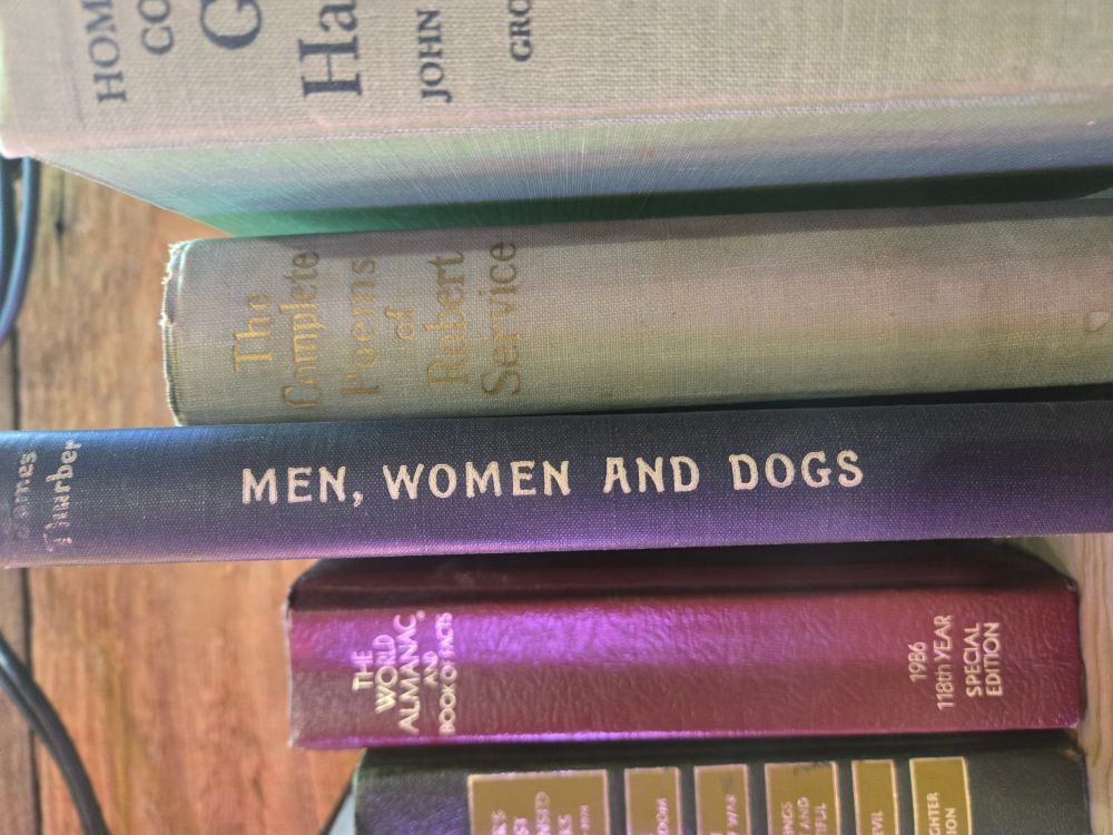 A stack of books. One of them is titled "Men, Women, and Dogs"
