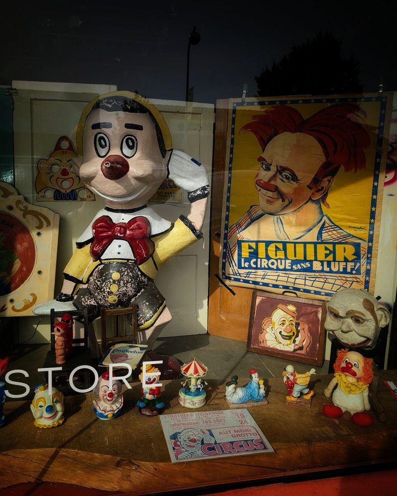 A store window with creepy vintage clown art and figurines. 