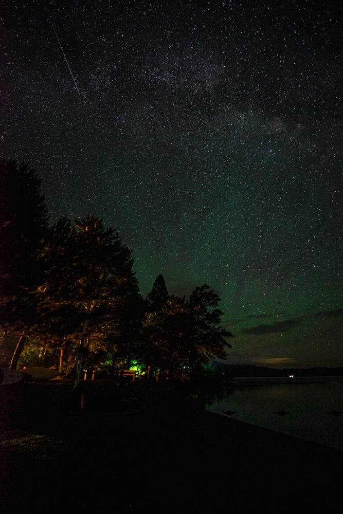 Green air glow coming in the sky with a meteor streaking in from the top left