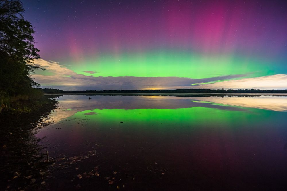 Northern lights over water creating symmetry 