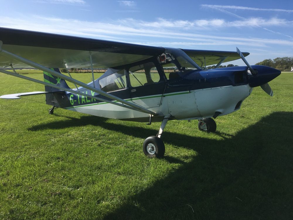 Decathlon aircraft sitting on a grass airfield on a sunny day.