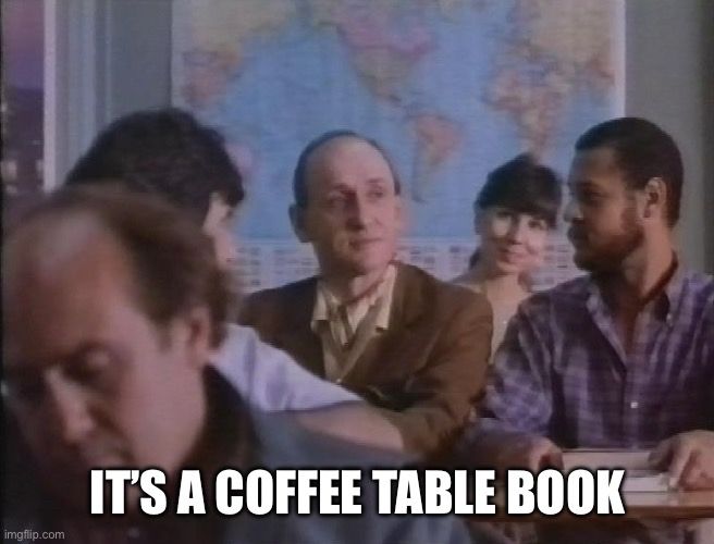 Still from “Throw Momma From the Train” of a man in a brown suit in a crowded classroom. Caption: IT’S A COFFEE TABLE BOOK