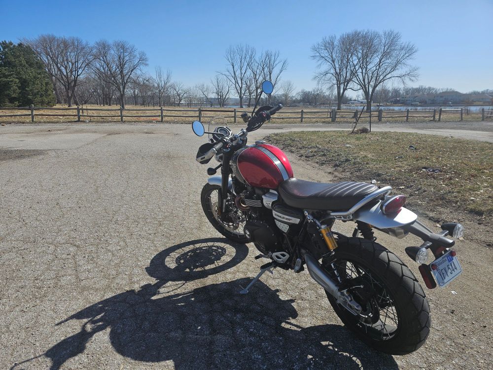 Triumph Scrambler 1200 parked near Carter Lake, north of downtown Omaha. Eppley Airfield parking garages just visible through the trees in the background.