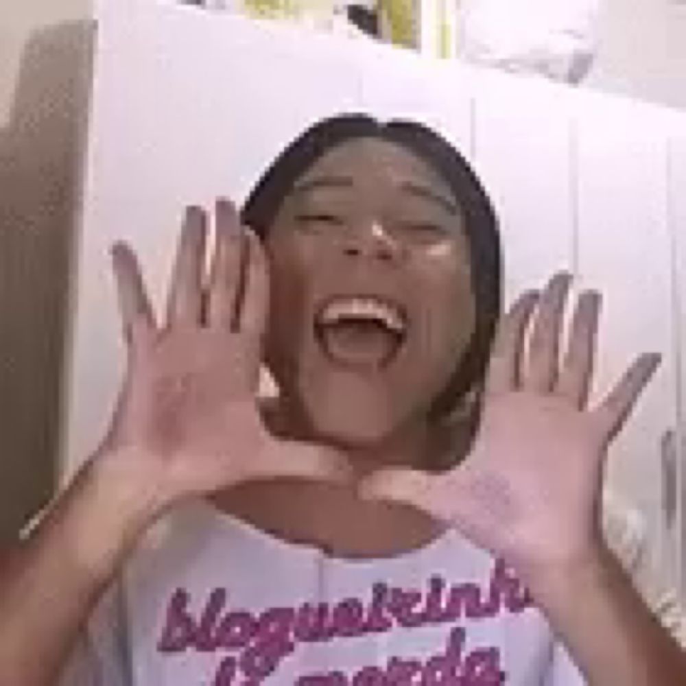 a woman is making a heart shape with her hands and laughing .