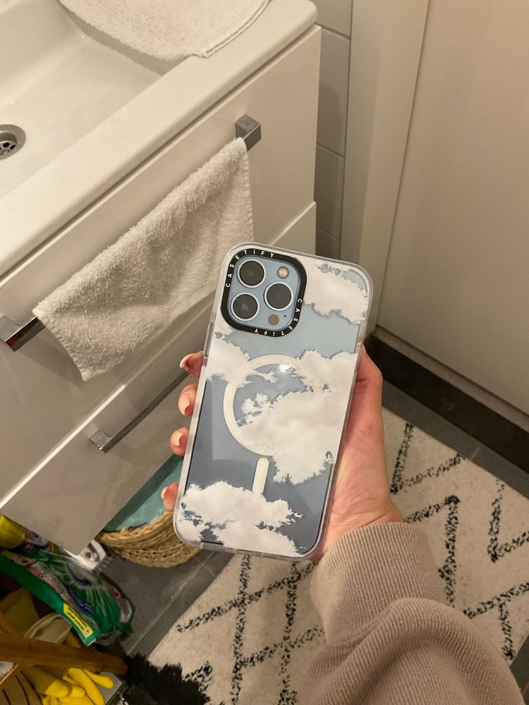 An iPhone with a clear MagSafe case with clouds, by casetify.