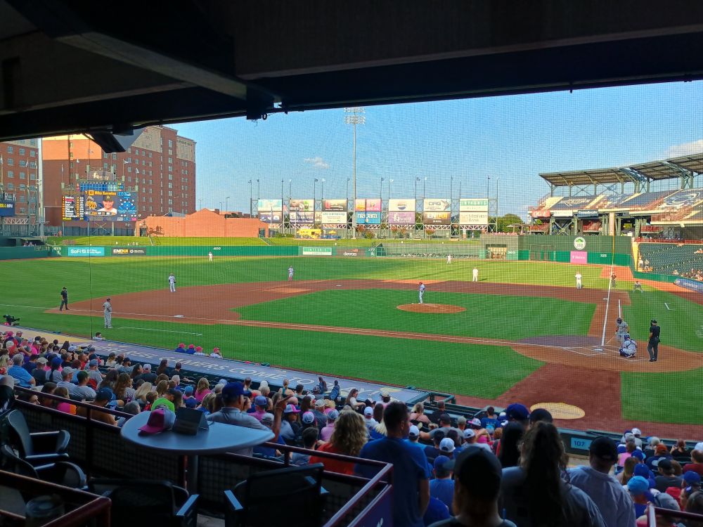 A photo from behind home plate, toward the third base line, looking out across the stands and a full field of players.