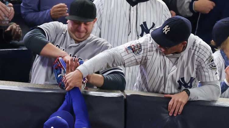 Two Yankees fans interfere with a play, and try to wrestle away a ball from a dodgers player.