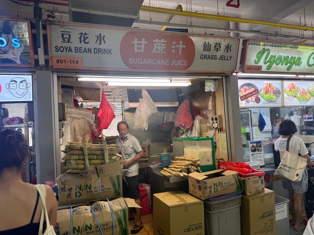 Stall that just sells sugarcane juice and soya bean drink. There are pieces of sugar cane scattered on the counters. 