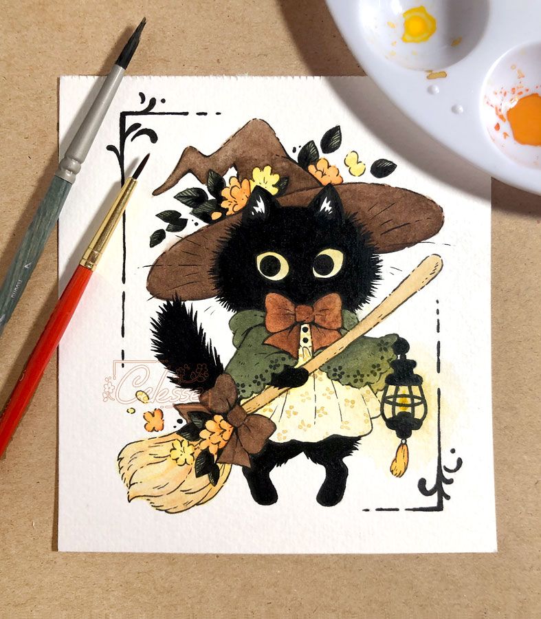 A photo of a watercolor painting of a fluffy black kitten witch wearing a dark brown hat, a simple beige floral dress and a green cloak with a big brown bow at the neck. She holds a broom in one paw and a lantern in the other. Two paintbrushes and a paint pallet are on either side.