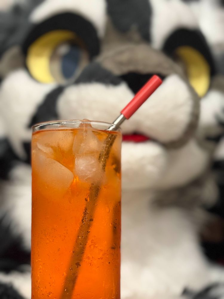 An Aperol Soda in front of a cat fursuit head.