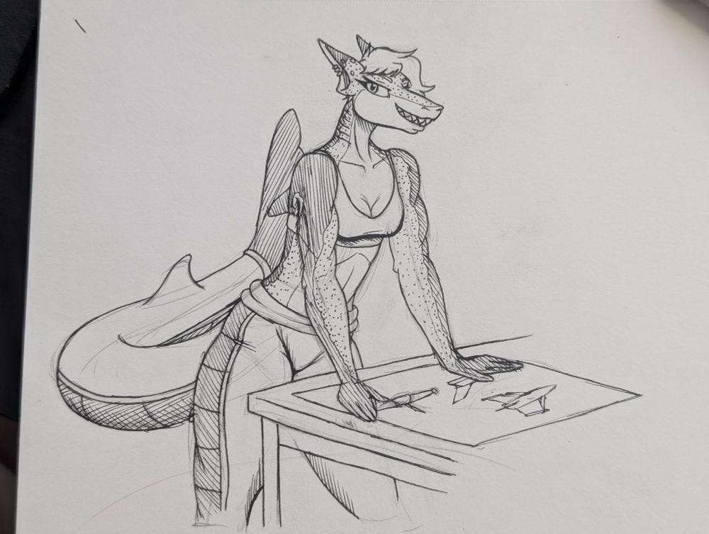 Jann, an anthropomorphic shark woman, leaning over a design diagram with an exciting look on her face and her suit down around her waist and a bra on.