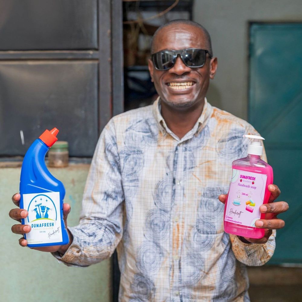 Hilton Nyambua, who runs Duma Fresh Enterprises, showing two of his products. He is smiling and holding them out to the camera. 