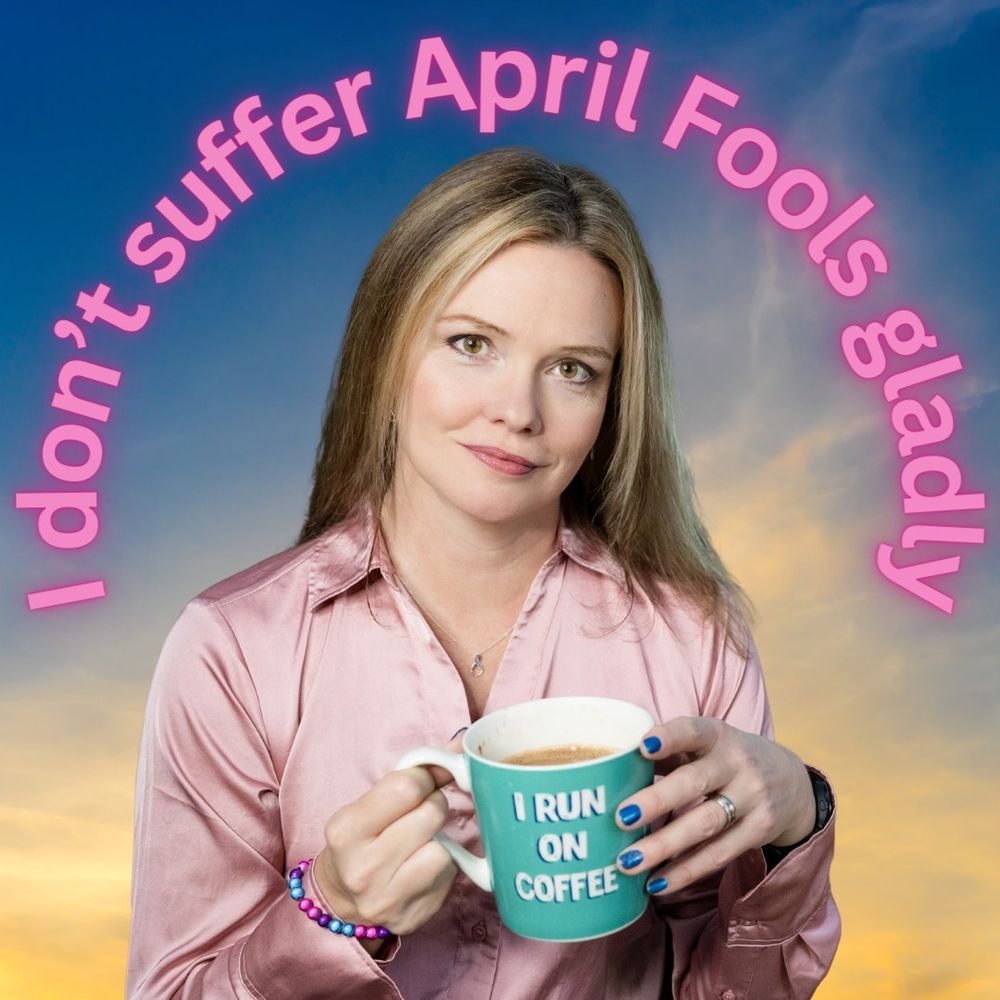 Photo of Charlie, a white woman in her late forties with straight blonde-highlighted shoulder-length hair, staring intensely at the camera, wearing a pink satin shirt, metallic blue purple and pink bead bracelet, metallic blue nail polish, and infinity symbol necklace, holding a mug that says I run on coffee. Large text curved around her head says I don't suffer April Fools gladly.