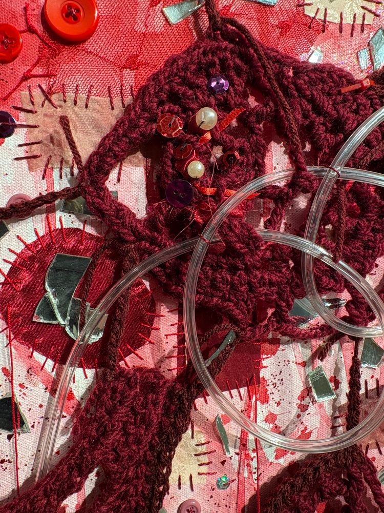 Detail of the right hand canvas. Shows the crochet prices Weber with tubing, as well as the patches, broken mirror, red paint and glitter added to the canvas. 