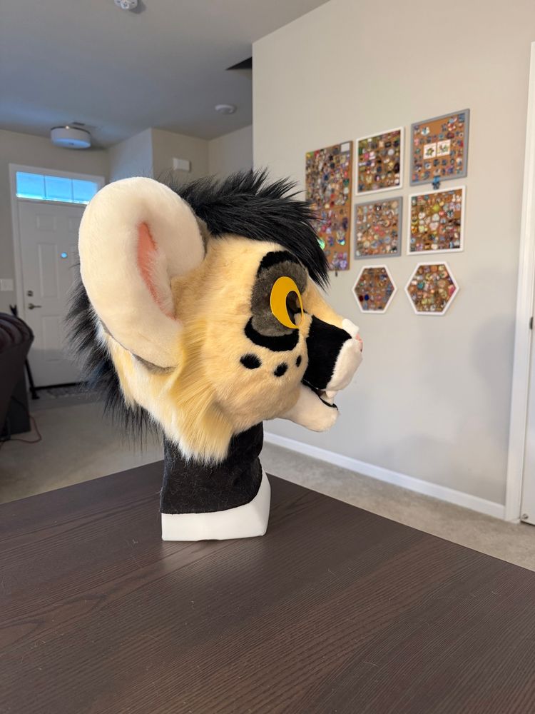 A photo of a fursuit head in progress of being made showing the side view of a happy puma big cat character.