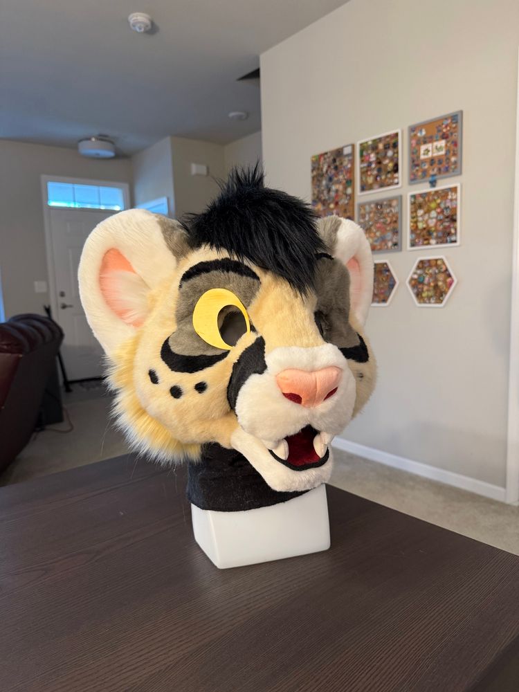 A photo of a fursuit head in progress of being made showing the front view of a happy puma big cat character.