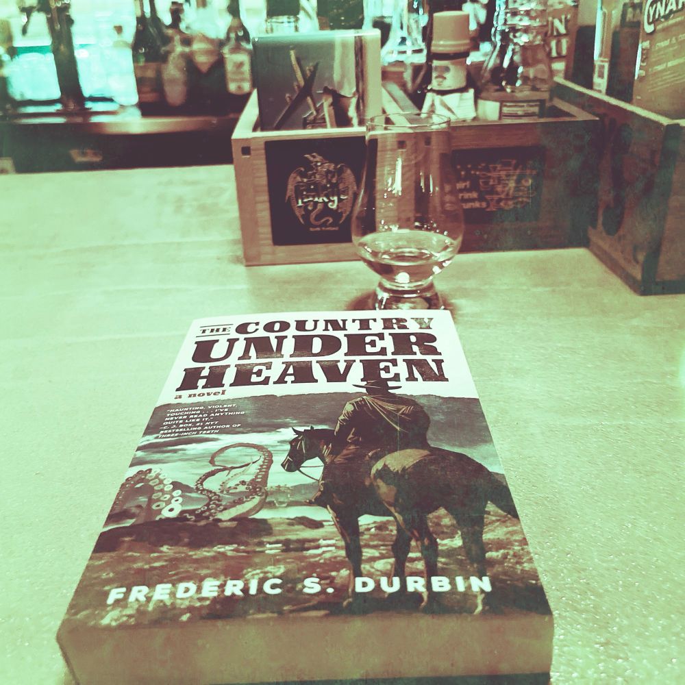 A copy of ‘The Country Under Heaven’ by Frederic S. Durbin and a complementary glass of bourbon.