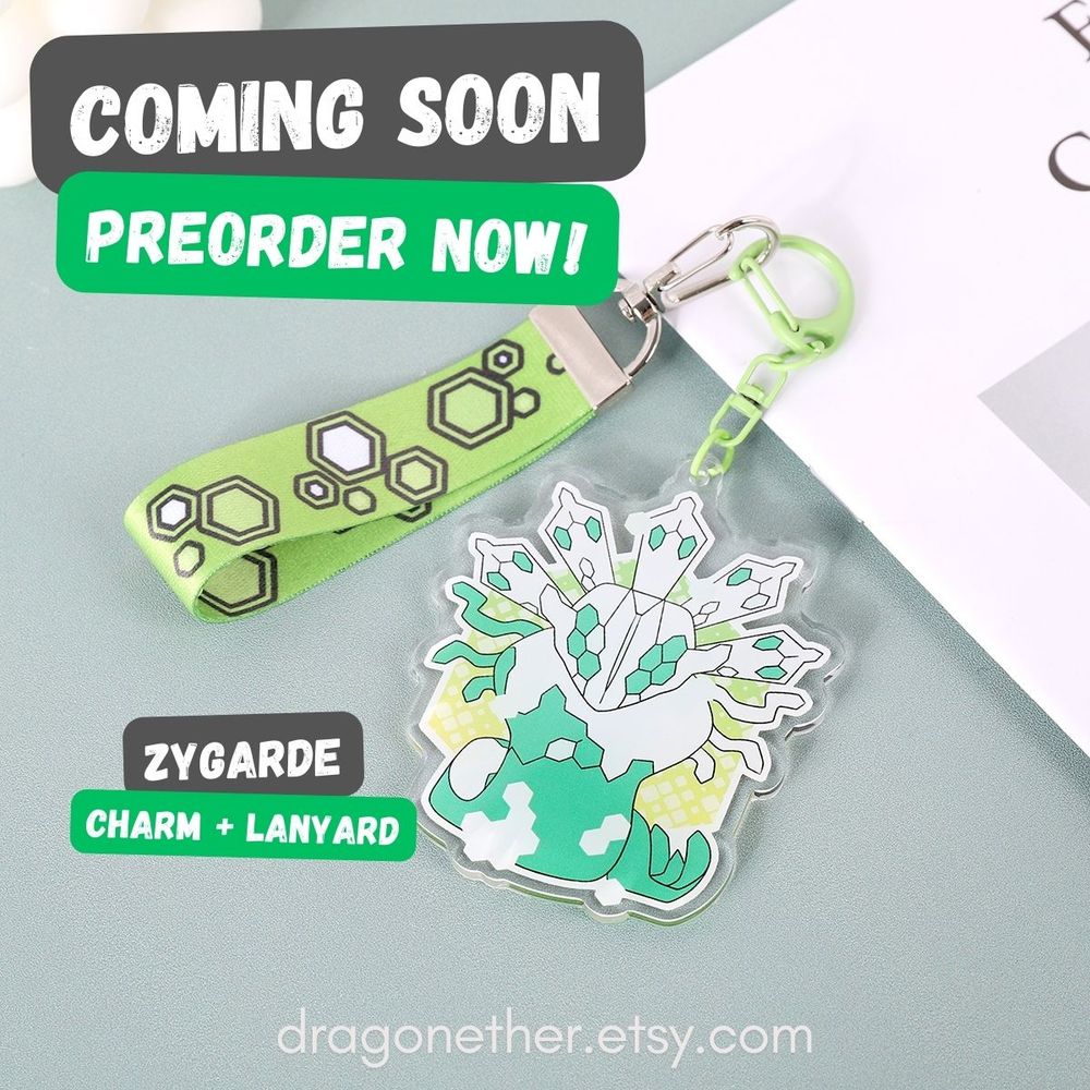 A photograph of a bright green and white acrylic charm of a Zygarde legendary Pokemon and lanyard for sale on Etsy.
