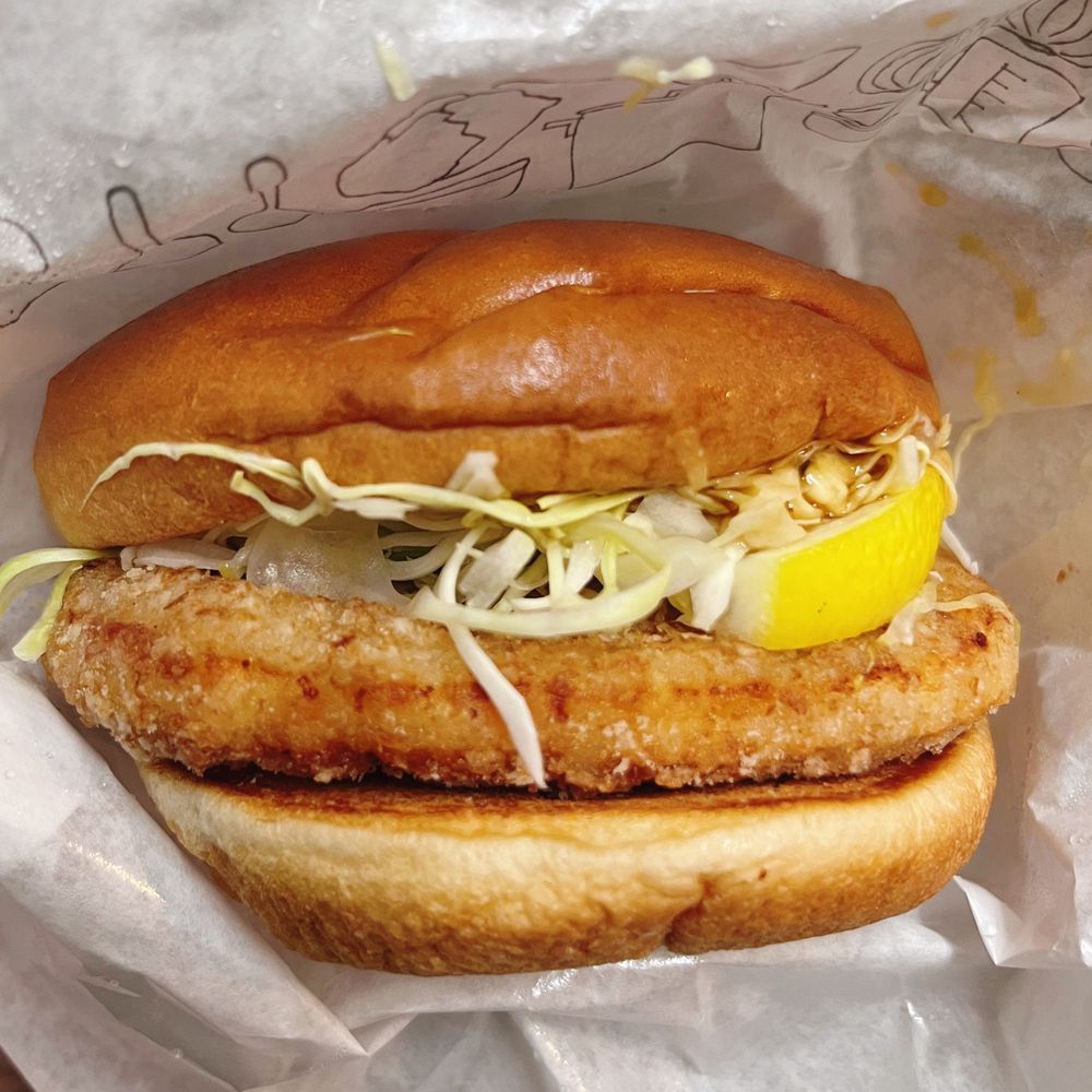 ハンバーガー。丸く大きな鶏の竜田揚げ、千切りキャベツ、レモンが挟まっている。