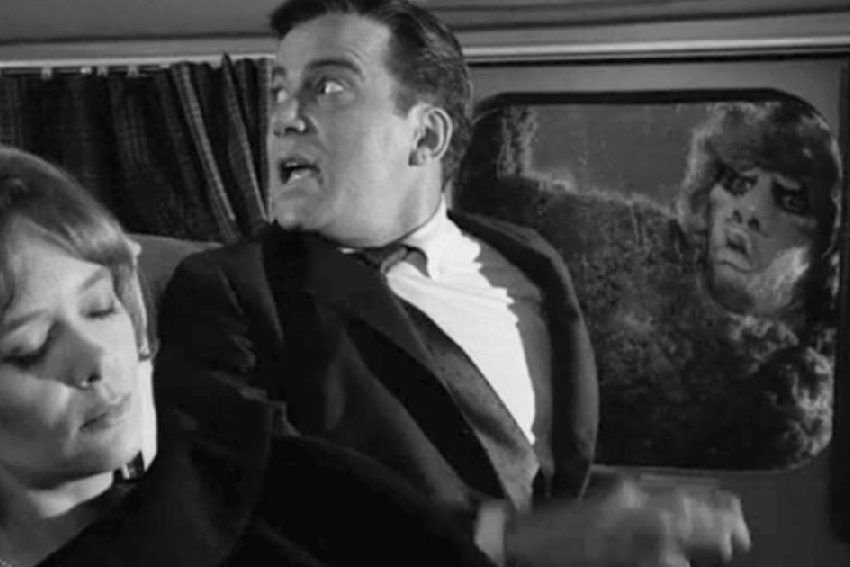 A black and white photo of a man (A very young William Shatner) in distress on a plane looking back for a stewardess, as a horrible monster is on the wing looking in at him. 