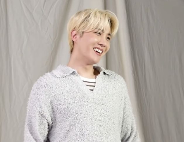 Blond Hobi in a grey knitted sweater, laughing big