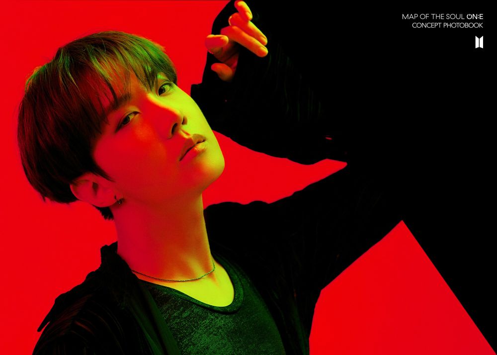 Jhope in a black sweater posing, behind him a red and black background. A concept photo from the Map of the soul ON:E photobook