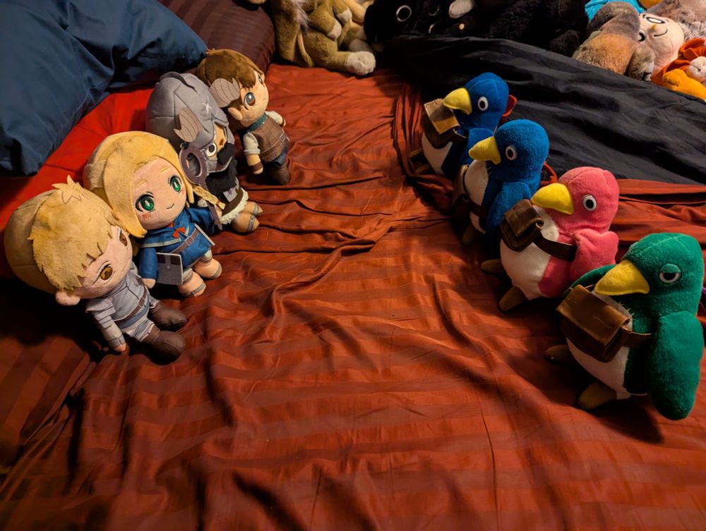 Plushies of the Dungeon Meshi group face off with plushies of Prinnies from the Disgaea games.