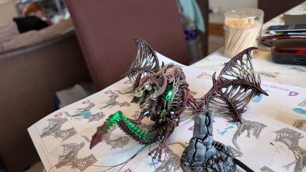 Three pictures of an undead dragon burning from within with a green fire (actually two LEDs one in the mouth and one in the chest). It's a Dungeons And Lasers plastic kit called Thall and it's another work of staggering genius by a towering artistic colossus of the miniatures world (I. E. It's been painted to a moderate standard by an ape with a sponge)