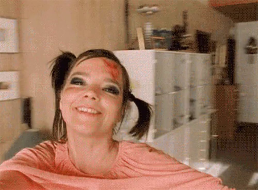 a woman with pigtails has blood on her face and is smiling .