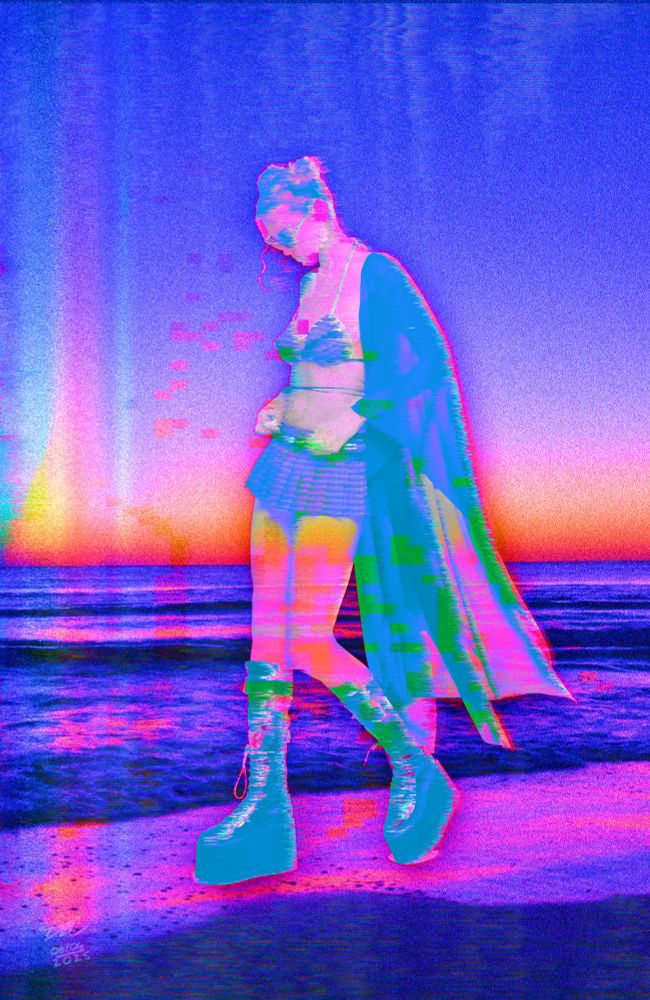A fem presenting human is dressed in Goth clothing and wearing sunglasses while walking at the shoreline. Everything is in blues, pinks with some yellows and greens, and looks glitchy and somehow digitized. 