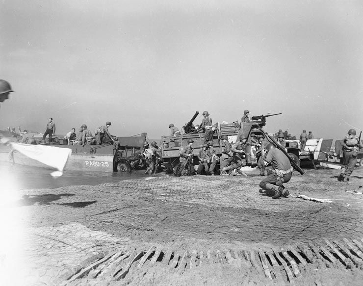 Artillery being landed during the invasion of mainland Italy at Salerno, September 1943. Troops bringing artillery ashore at Salerno in September 1943. The military policeman (MP) in the foreground is ducking from a near-by German shell hit. The LCVP is from USS James O'Hara (APA-90). Note the use of chicken wire to stabilize the beach sand. Official U.S. Navy Photograph, now in the collections of the National Archives and Records Administration, Still Pictures Unit, College Park, MD. Photo Citation Number: 80-G-54600. Official Caption: "American fighting men pour out of their landing ships. The M.P. in the foreground was in the act of instinctively ducking from the blast of a shell from a German 88mm. gun."