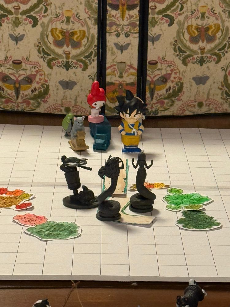 A mat composed of small squares with random cat gashapon, Goku and a hello kitty figure