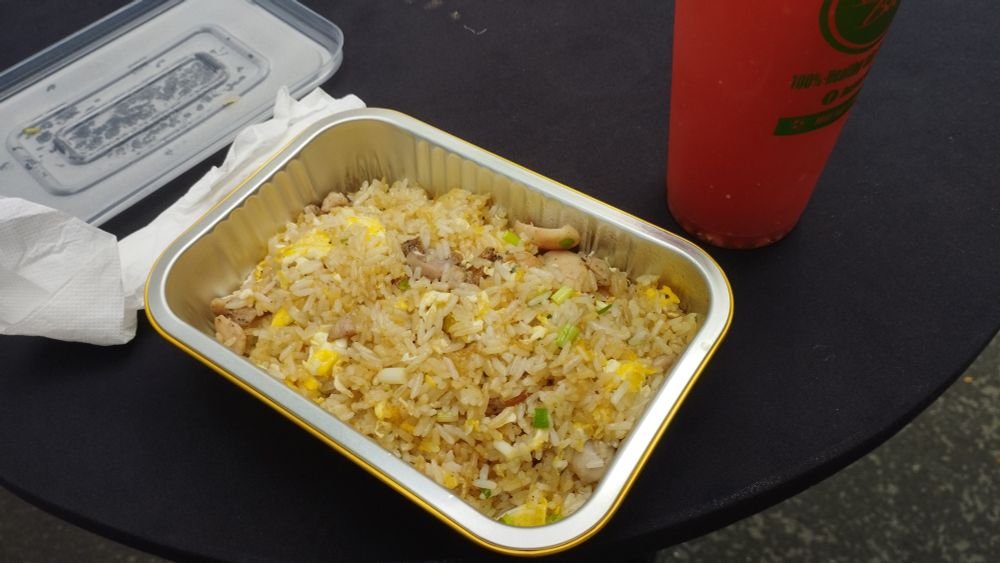 Un cajon de chaufa con un vaso alto de jugo de sandía