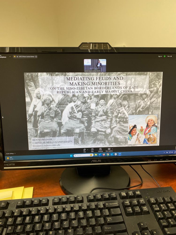 Photo of a computer screen showing a PowerPoint slide and inset of a man standing at a lectern. 