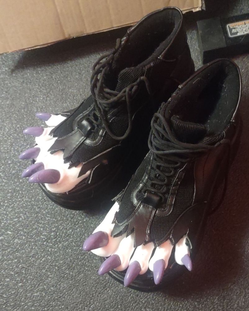 Overhead view of black Demonia 4 inch platform shoes with the fronts torn open and white clown toes popping out of the front, with shiny purple claws 
