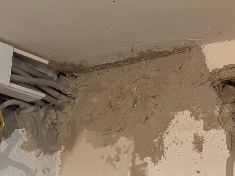 Kabel kommen aus der Wand und verschwinden im Kabelkanal. Grob verputzt. 