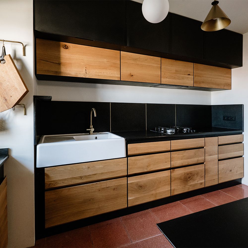 Dulapuri de bucătărie cu sertare din lemn de stejar cu fibra continuă. Chiuveta este din ceramică și iese ușor din planul mobilierului. La partea de sus există două rânduri de dulapuri suspendate, din care primul este mai retras și cu uși din lemn. Dulapul de sus este din placaj vopsit negru cu muchii teșite.