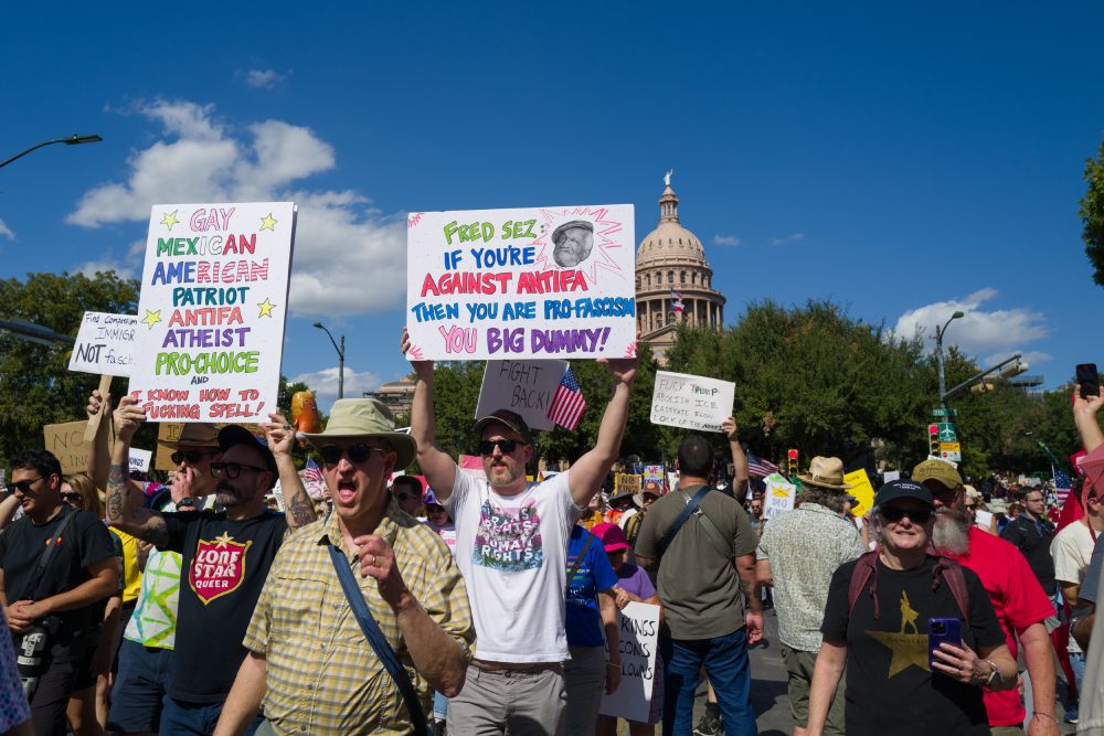 No Kings Protest - 2025/10 Austin, Texas. Procession on Congress Avenue South of the Capitol.  Many people with signs and man in the middle of yelling. 