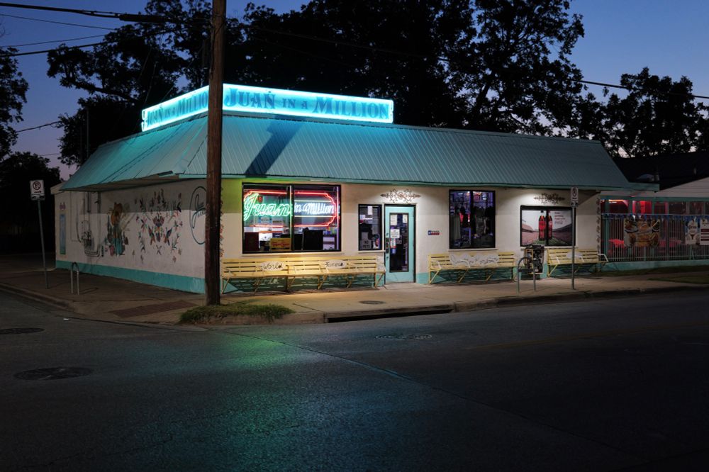 A corner view of the entire Juan In A Million restaurant in the morning’s twilight with all the neon lit and no cars yet.  