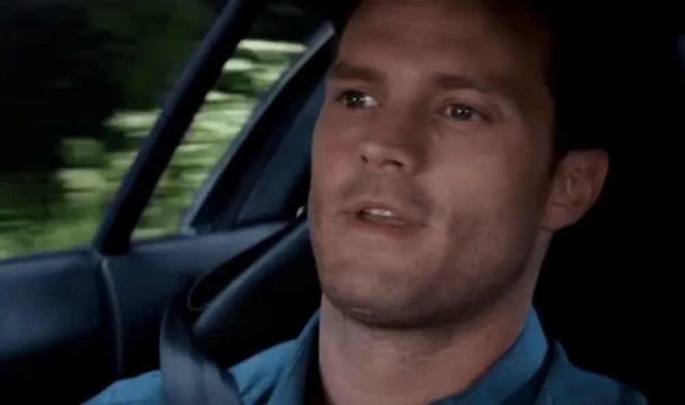 a man in a blue shirt and tie is sitting in a car