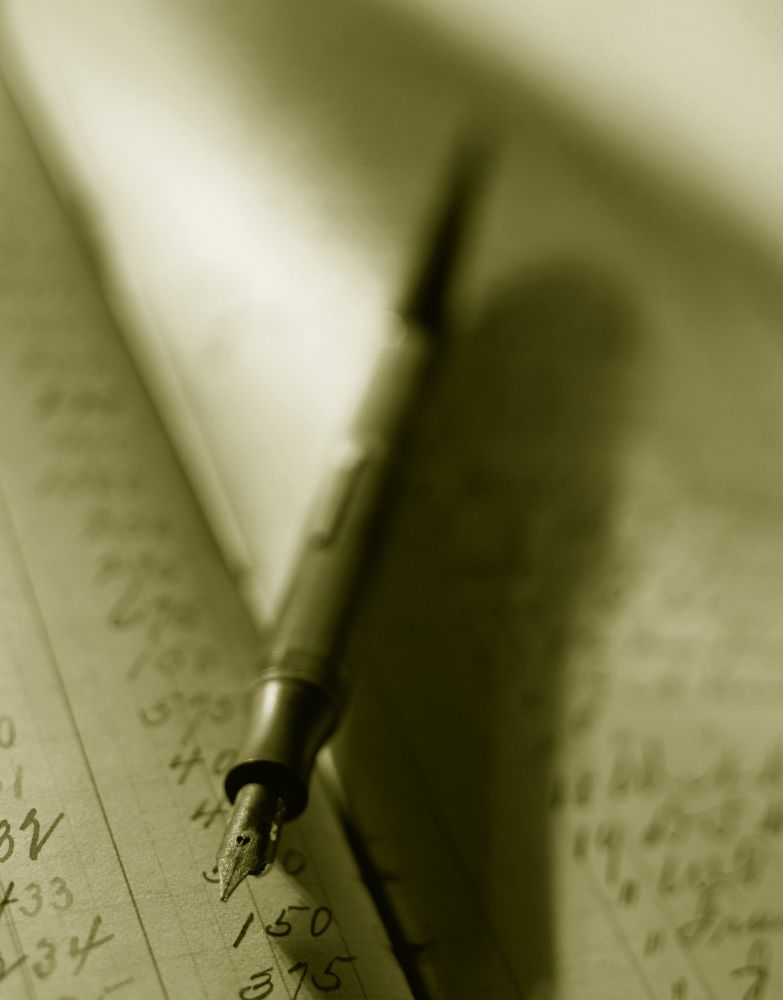 An image of a fountain pen laid across a notebook