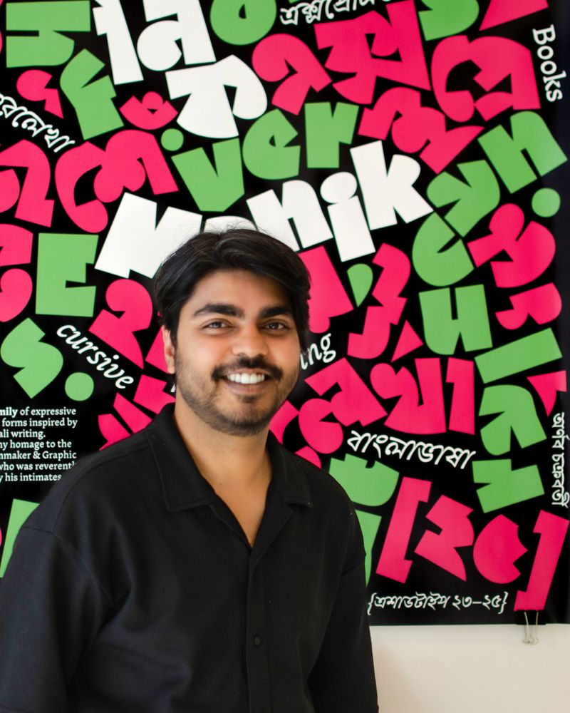2025 Gerard Unger Scholarship merit winner Arnab Chakraborty with a poster made with Manik in the background.